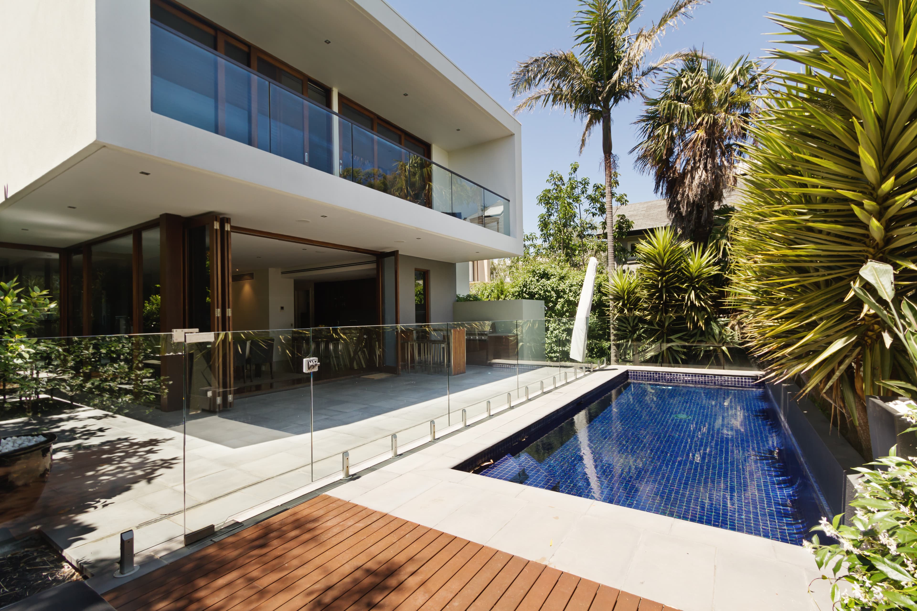 Varanda de casa de luxo com portas de esquadria de alumínio, muito arborizada com uma piscina ao meio